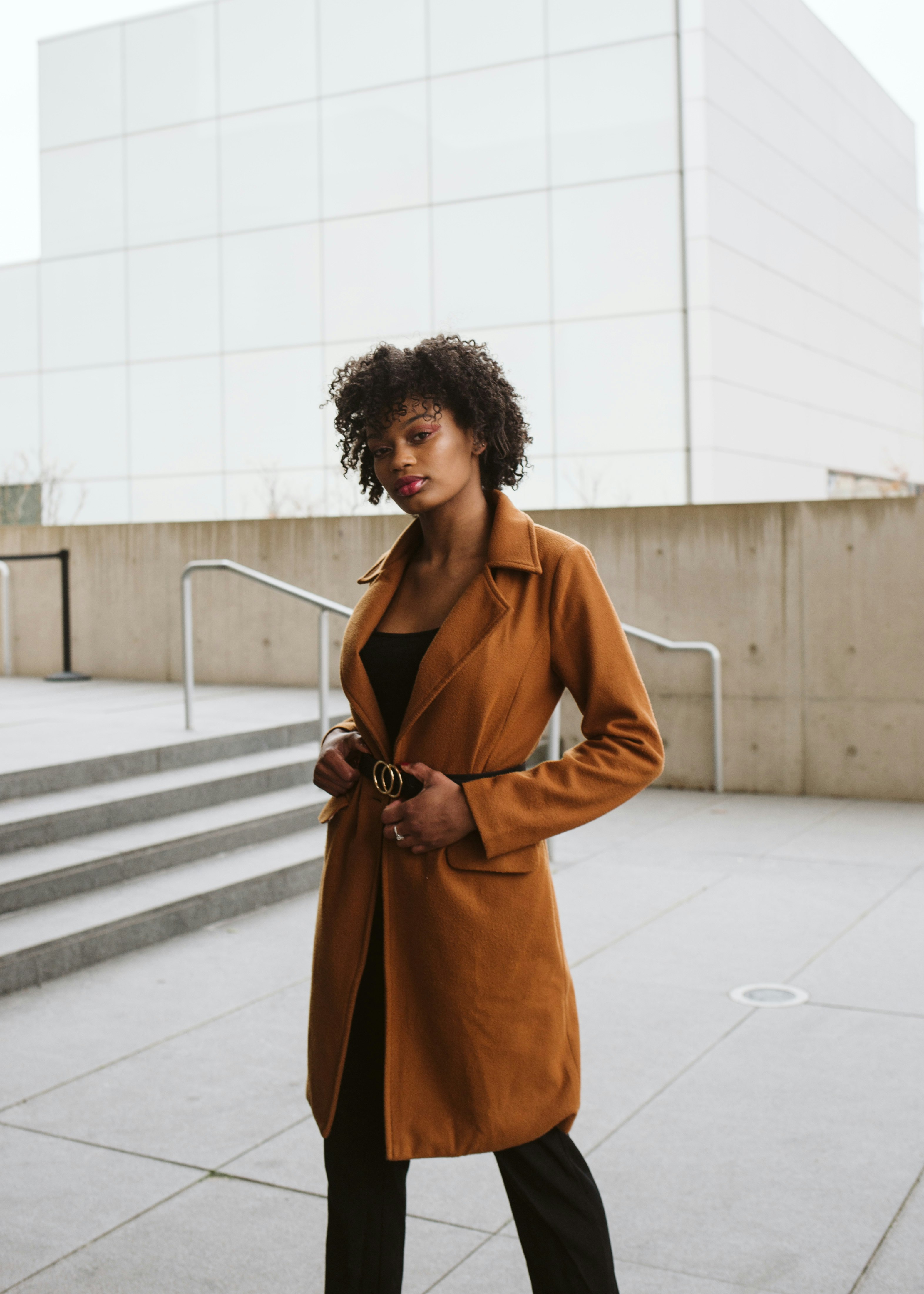 woman in brown coat standing on white floor tiles